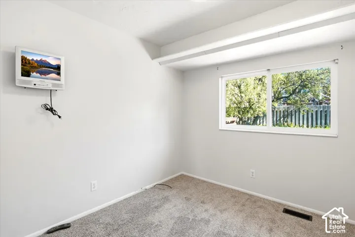Large window offering natural light, light-toned walls, and neutral carpeting