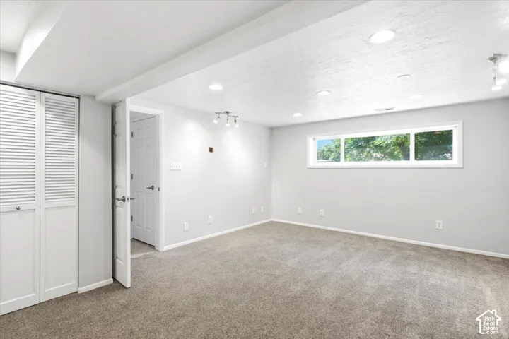 Carpeted room featuring a white-framed window, recessed lighting, and white bi-fold closet doors