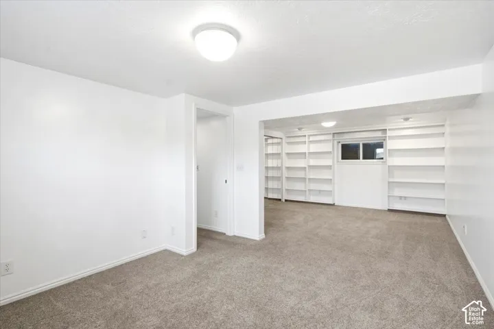 Recessed ceiling lighting, built-in shelving, window, and neutral carpeting
