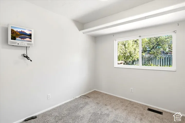 Large window offering natural light, light-toned walls, and neutral carpeting