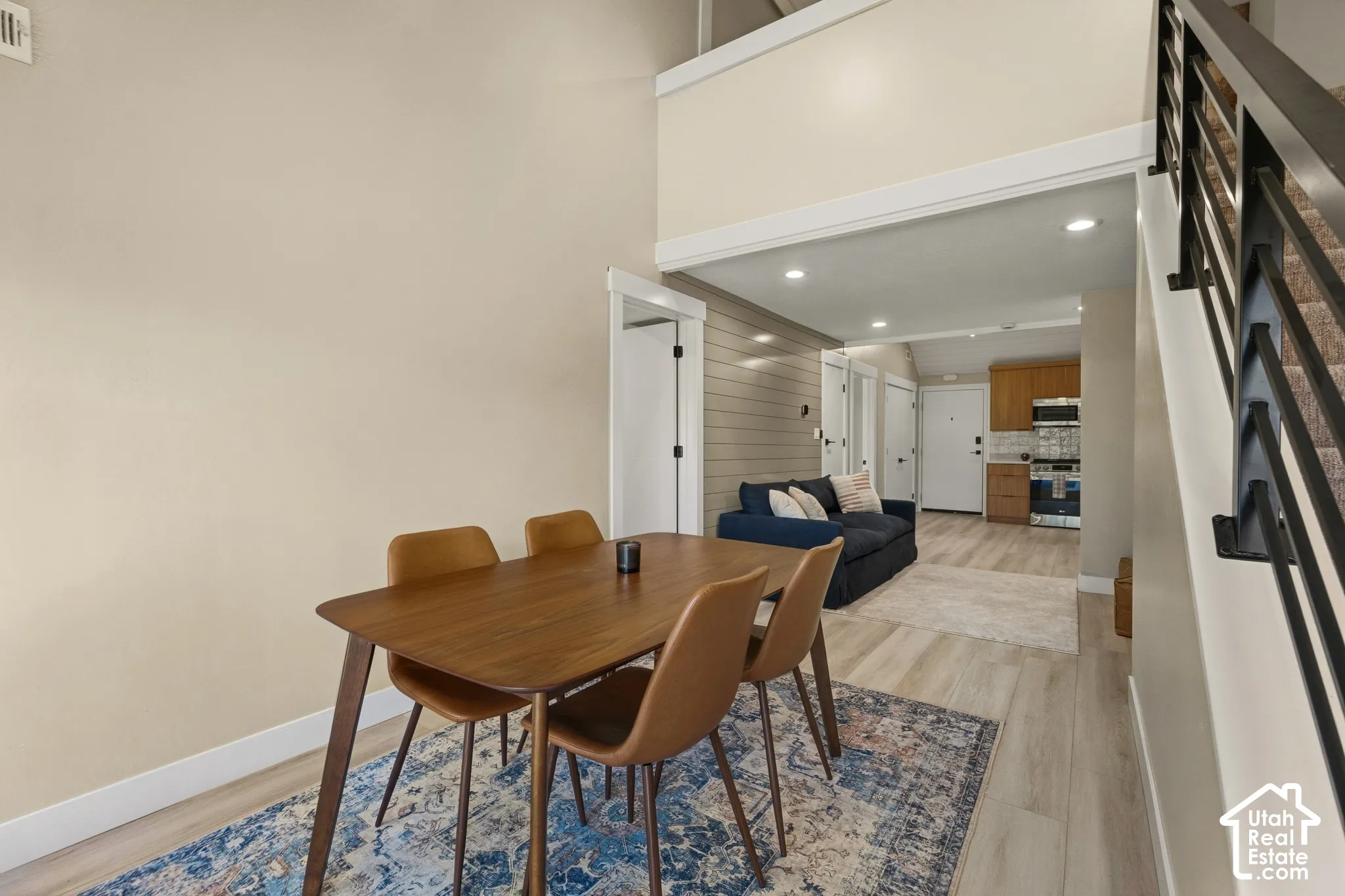Open-concept living space with high ceilings, recessed lighting, wood-finish flooring, and a modern staircase with black railings