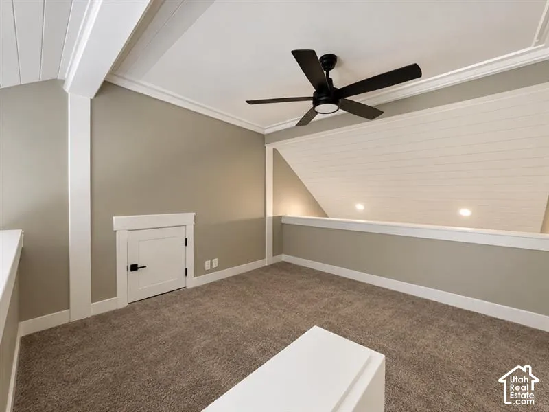 Carpeted loft area featuring a ceiling fan, recessed lighting, accent wall paneling, and an integrated storage door