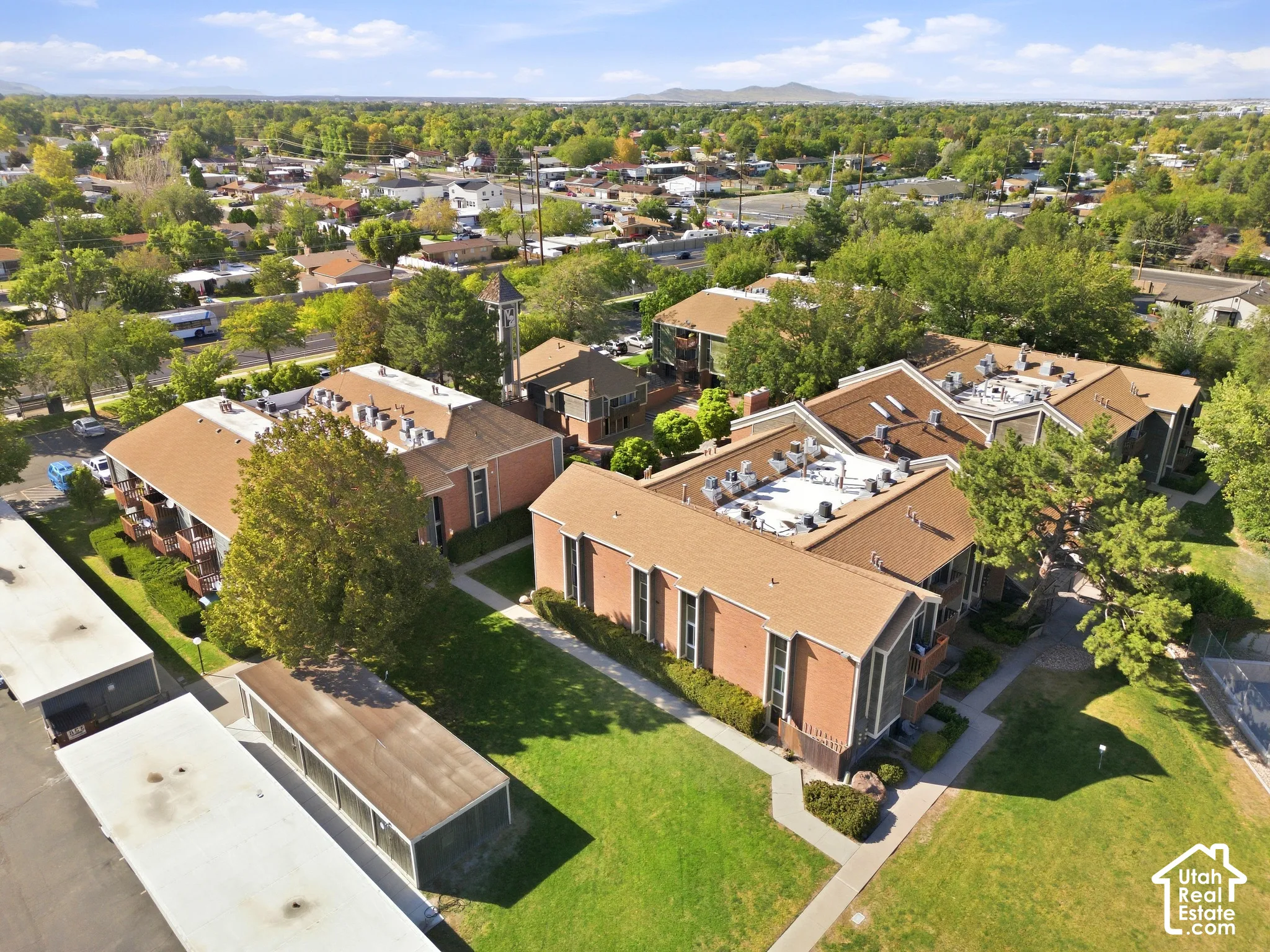 Multiple multi-story buildings featuring brick exteriors, pitched shingle roofs, and individual balconies