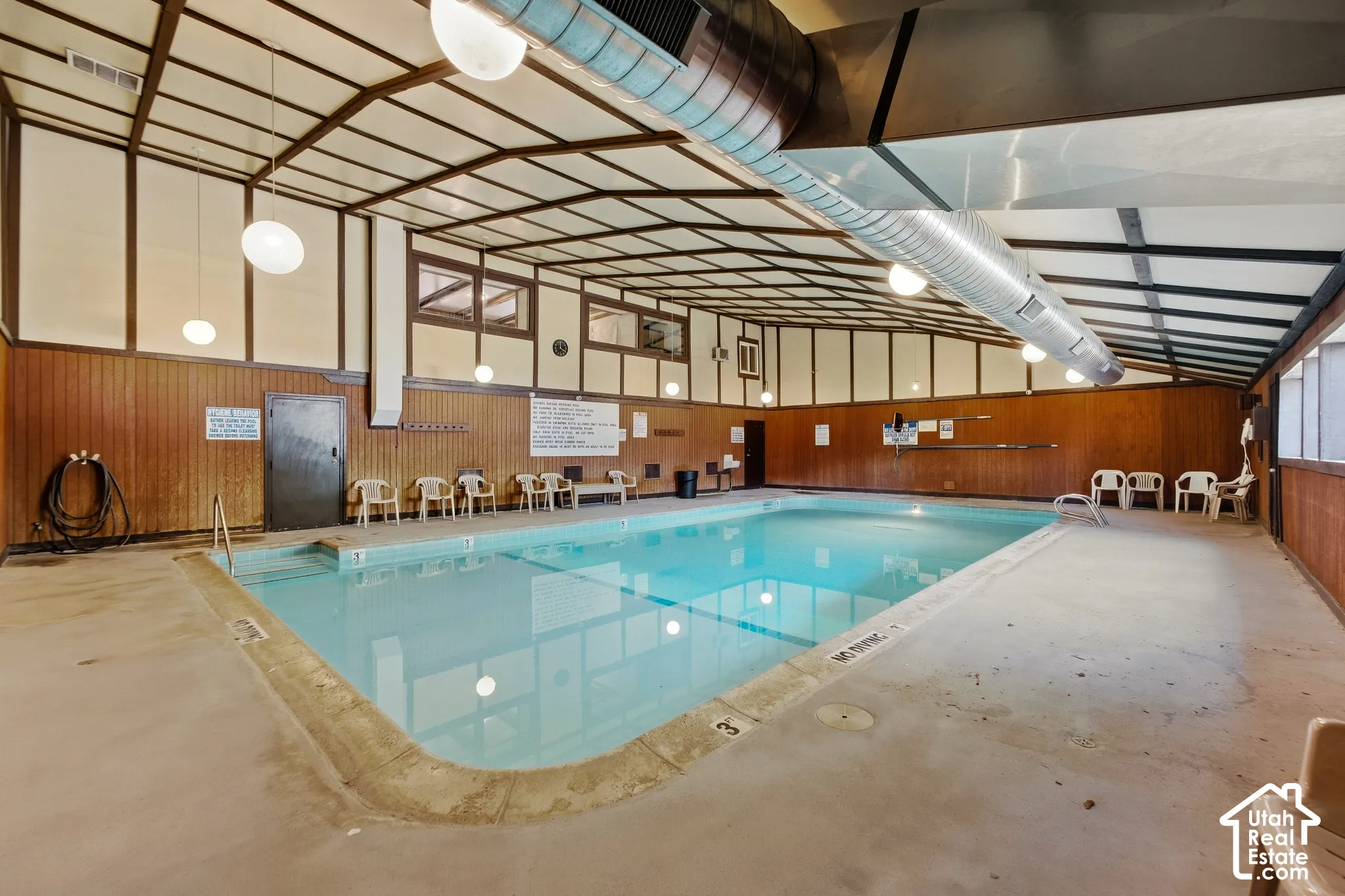 Indoor swimming pool with concrete decking and wood-paneled walls
