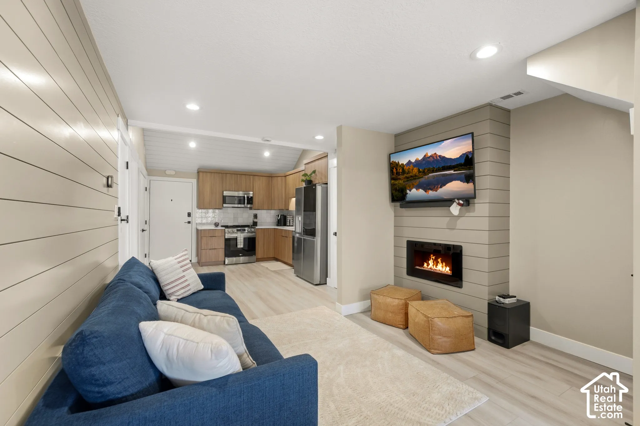 Open-concept living area featuring a built-in fireplace, wood-finish flooring, recessed lighting, and a shiplap accent wall