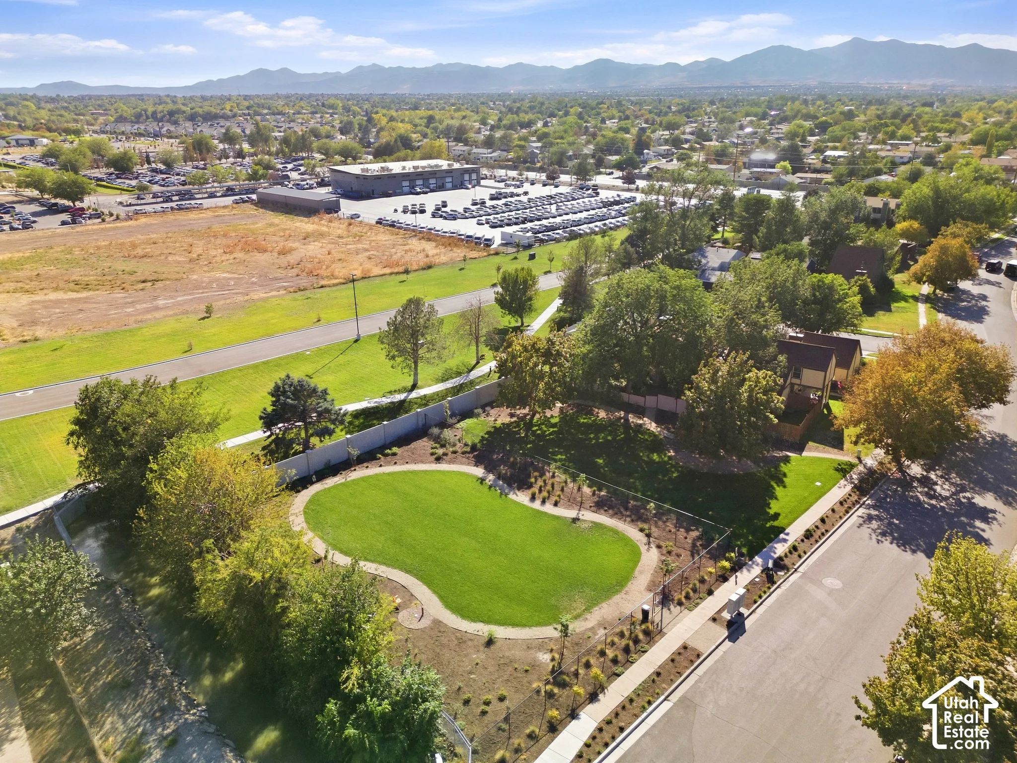Expansive property featuring a paved road, mountain range, and a residential neighborhood with established trees