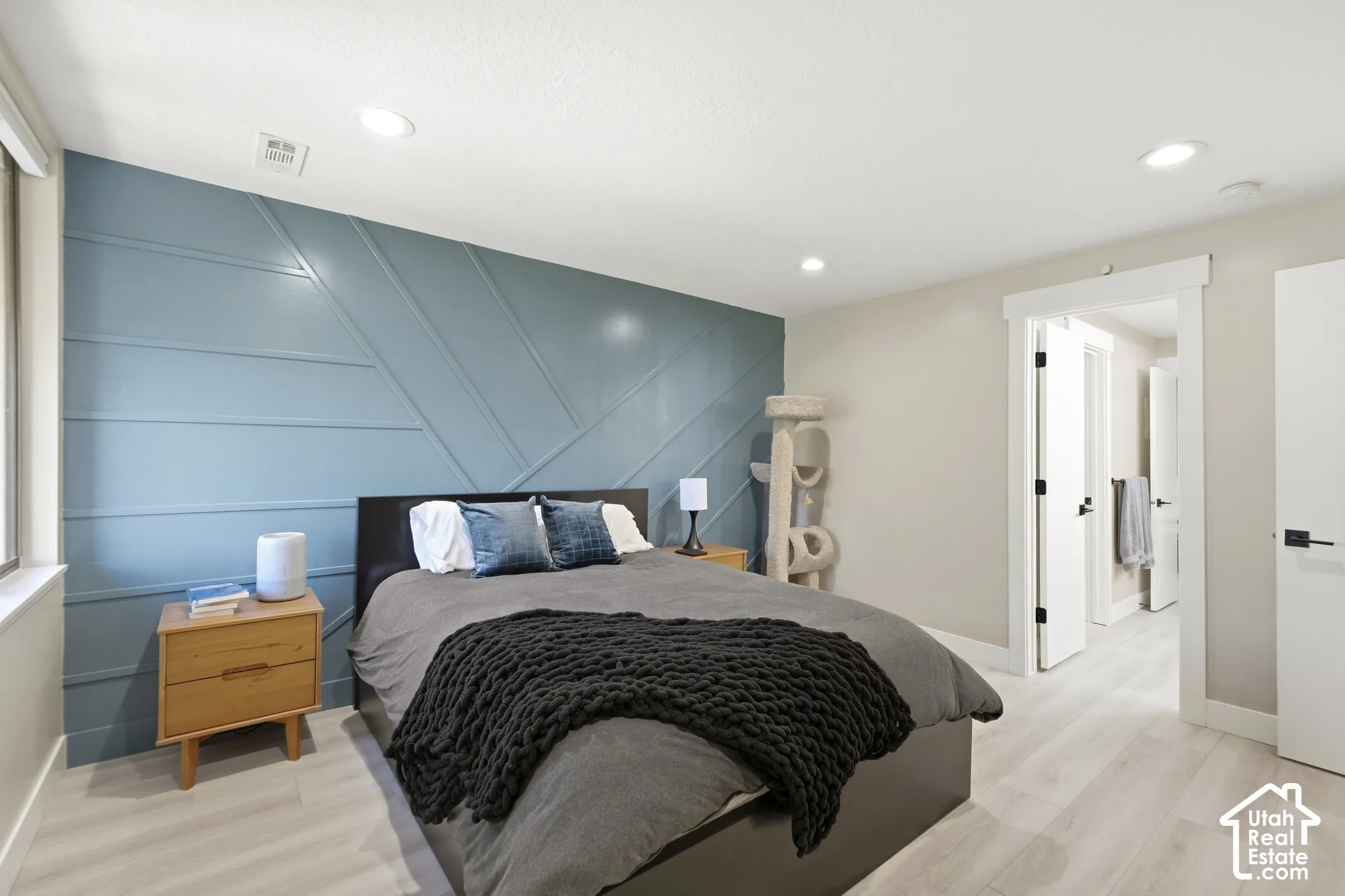 Accent wall featuring geometric paneling, wood-finish flooring, recessed lighting, and a white interior door with matte black hardware