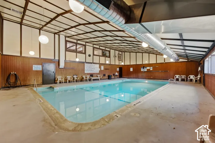 Indoor swimming pool with concrete decking and wood-paneled walls
