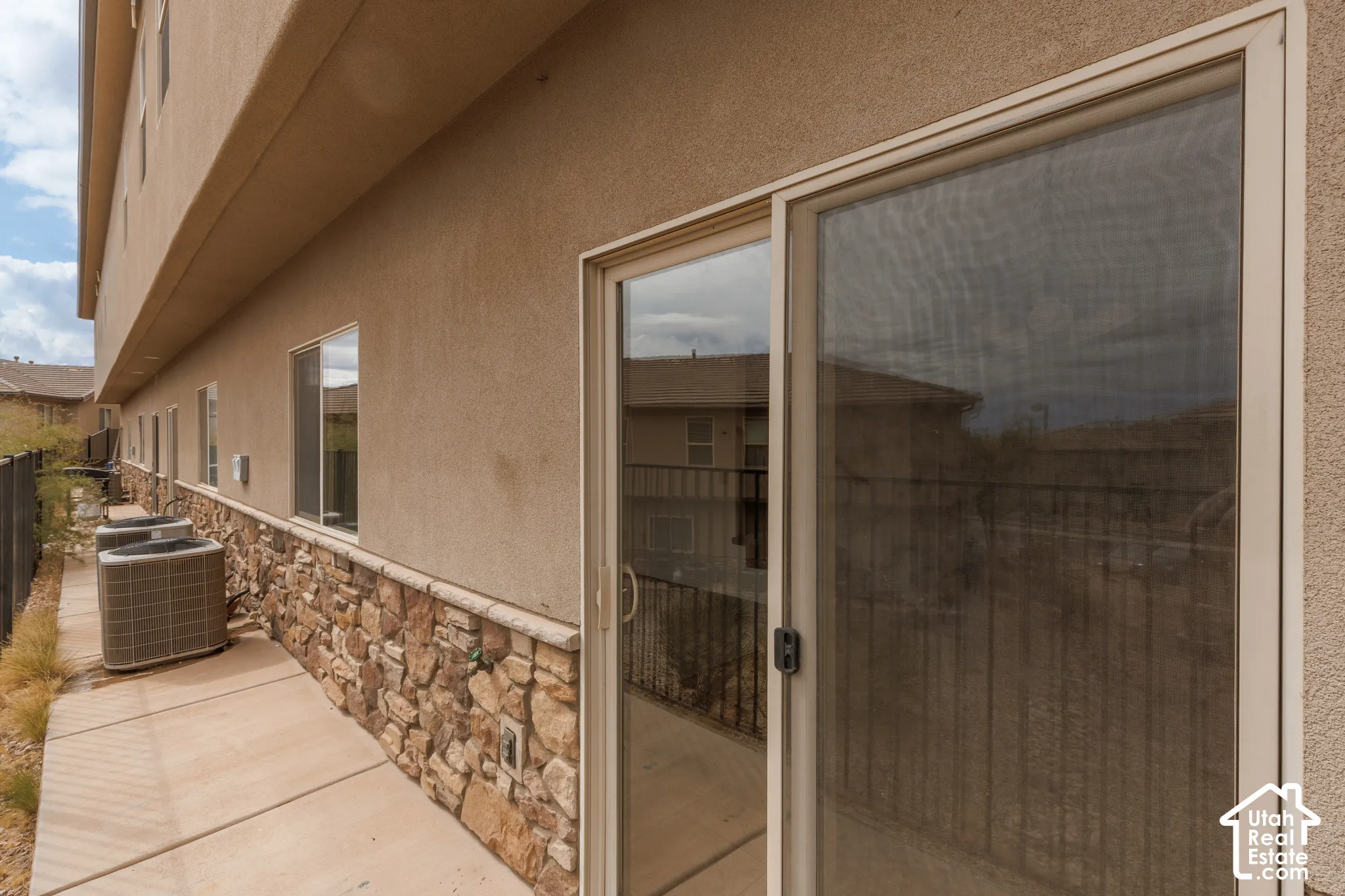Stucco exterior with stone veneer detailing, multiple windows, and a sliding glass door