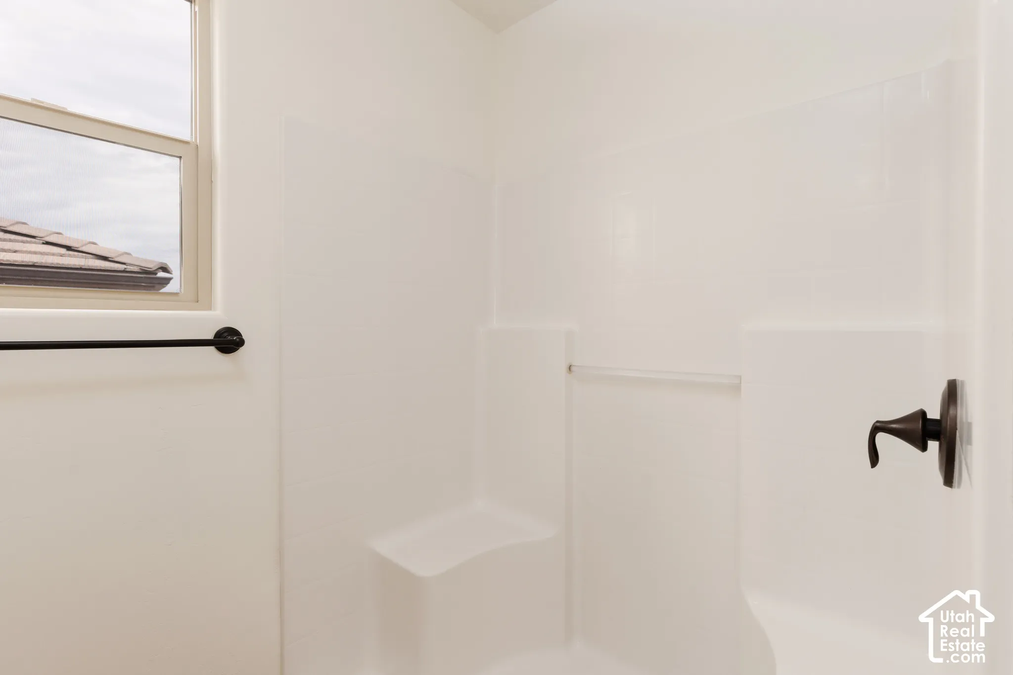 Shower enclosure with a built-in bench, oil-rubbed bronze fixtures, and a window