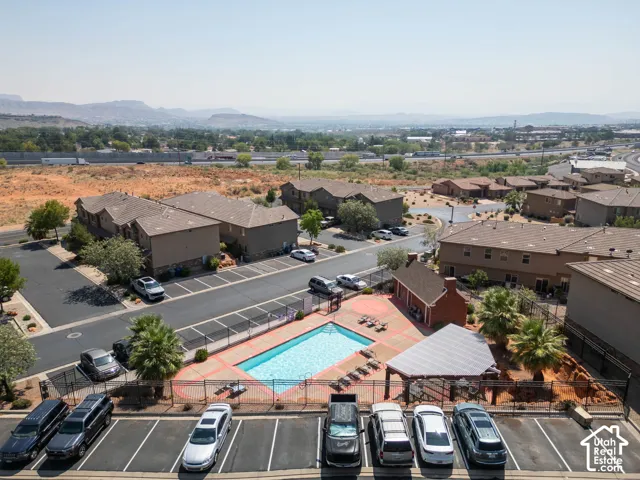 Community swimming pool with surrounding fence, adjacent shaded patio area, and mountain backdrop