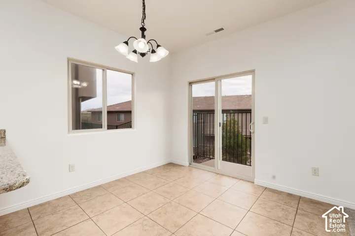 Tile flooring, sliding glass door, single window, five-light chandelier, and a granite-finish countertop