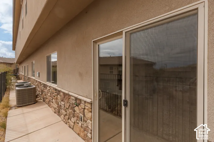Stucco exterior with stone veneer detailing, multiple windows, and a sliding glass door