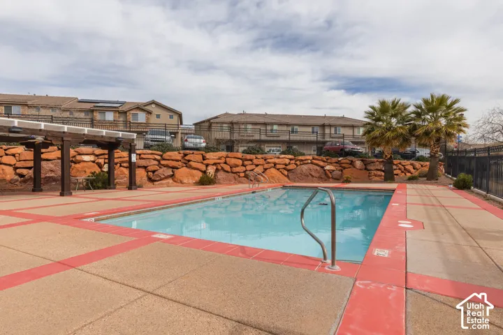 Outdoor pool featuring an integrated metal handrail, surrounded by a concrete deck with red accent borders