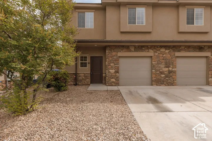 Stucco exterior with stone accent facade, two-car attached garage, concrete driveway, and front entry door