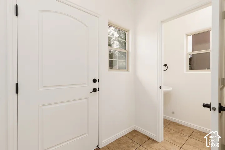 Arched panel door with matte black hardware, dual pane windows, and neutral tile flooring