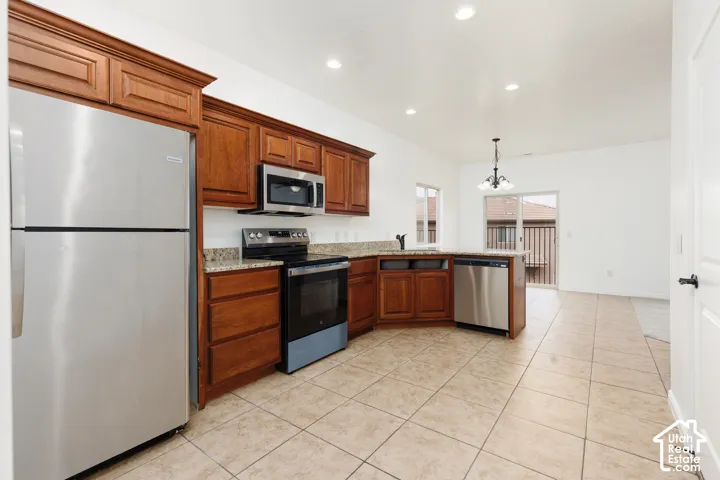 Kitchen with wood cabinetry, stainless steel appliances, granite countertops, and tile flooring