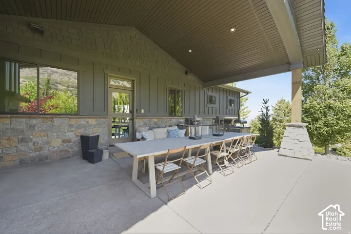 Expansive covered patio featuring a concrete surface, stone pillar, and recessed lighting