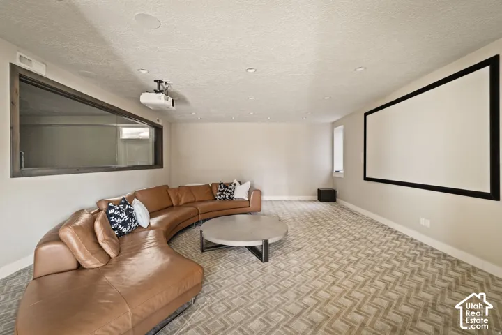 Dedicated media room featuring a large projection screen, mounted projector, and recessed lighting