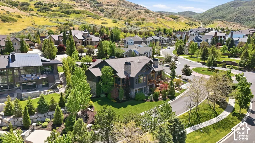 Contemporary residence with a dark-toned exterior and multiple gables, surrounded by mature trees and manicured landscaping