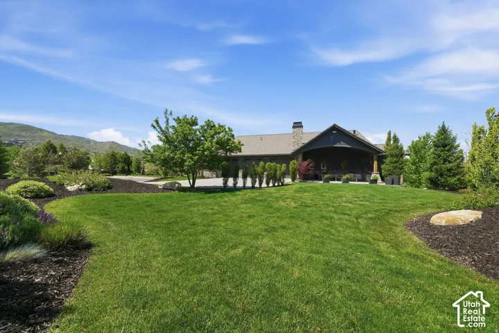Expansive green lawn with mature landscaping and decorative rock features