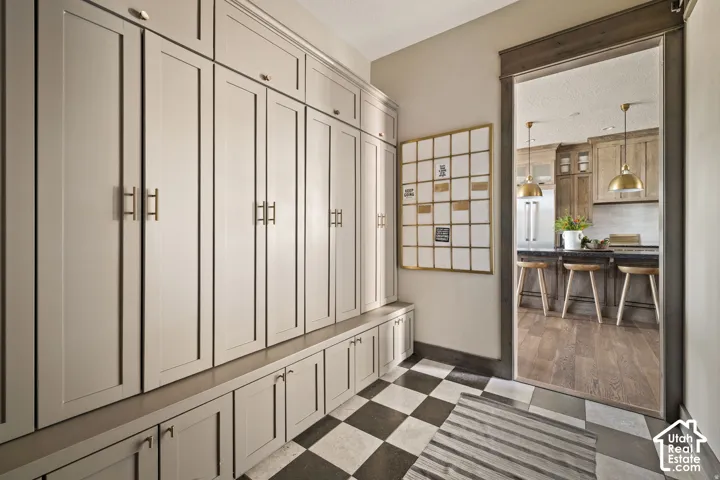 Built-in cabinetry with bench seating, brushed gold hardware, checkerboard flooring, wood-finish flooring, and a wide entryway