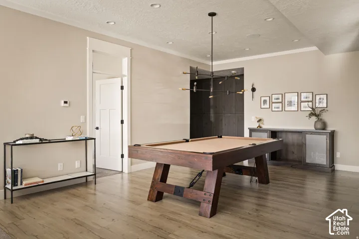 Wood-finish flooring, recessed lighting, and a modern chandelier illuminate this space