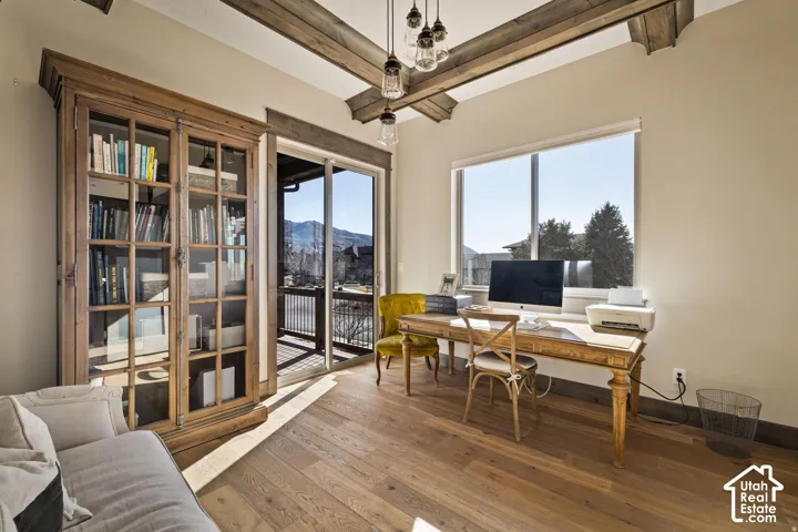 Hardwood flooring, exposed ceiling beams, built-in display cabinetry, sliding glass door to exterior, and a large picture window