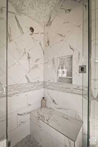 Shower enclosure featuring a built-in bench, marble-finish wall tiles, glass mosaic accent tile, an arched ceiling with mosaic tile, and a recessed niche