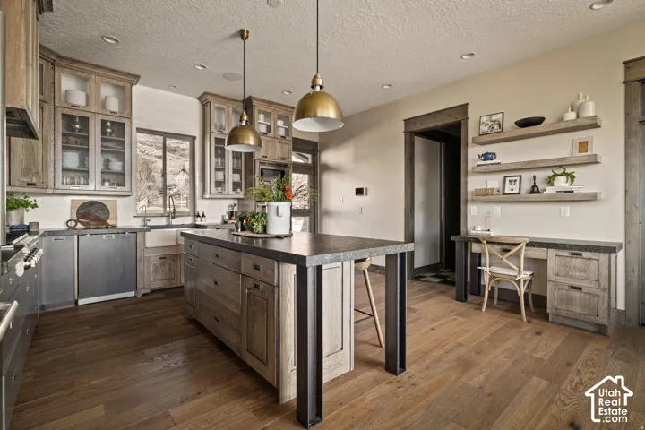 Kitchen featuring wood-finish flooring, a large island with a stone-finish countertop, recessed lighting, and integrated appliances