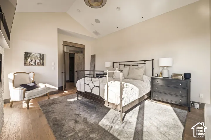 Vaulted ceiling, wood-finish flooring, built-in recessed lighting, and a double-door entry with wood trim