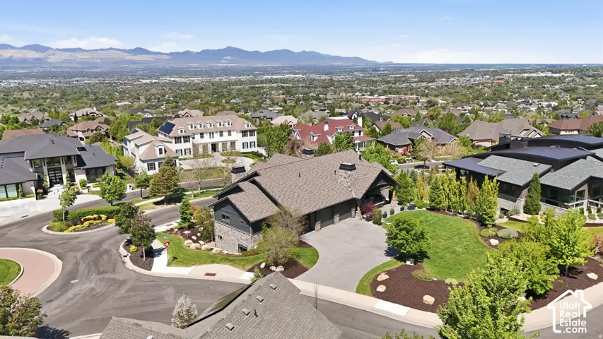 Stone and siding exterior with a multi-car garage, mature landscaping, and a sloped lawn