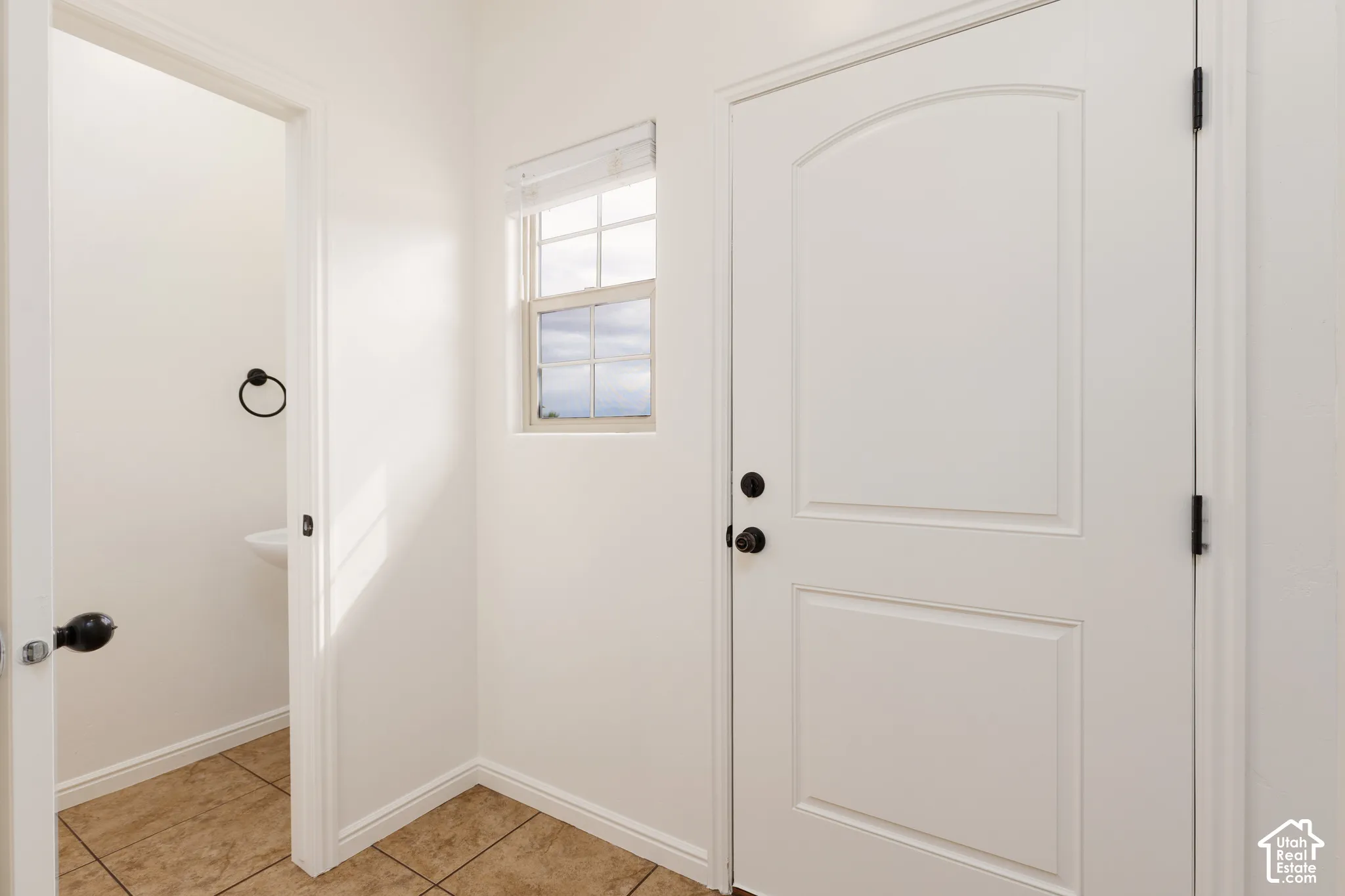 White paneled door with black hardware, complementing a framed window with blinds