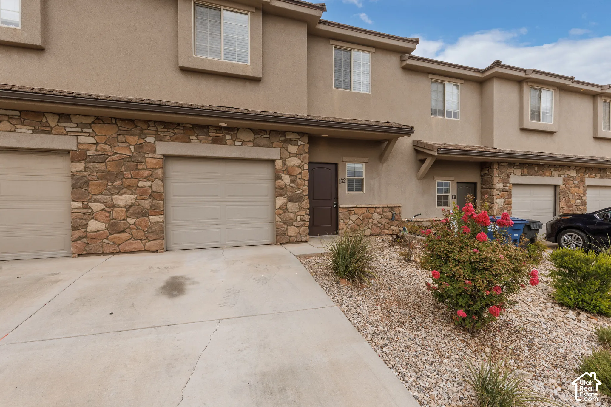 Stucco exterior with stone veneer accents, multiple windows, and an attached garage