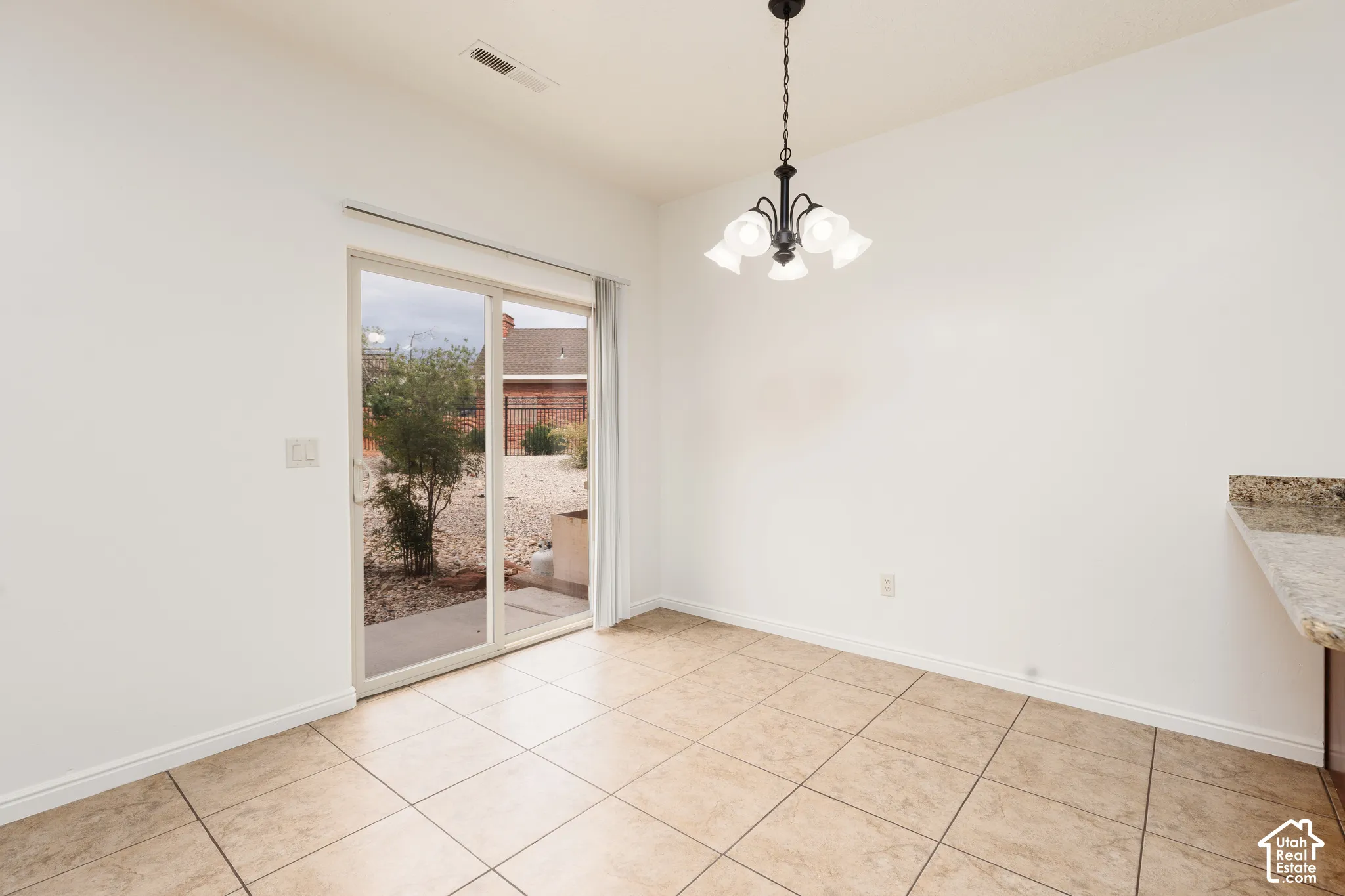 Tile flooring, sliding glass door, pendant light fixture, and a stone countertop