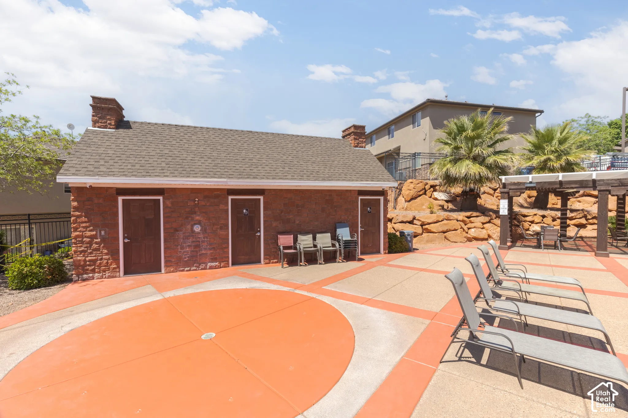 Stone-clad building with a shingled roof, paver patio, and an open-beam pergola