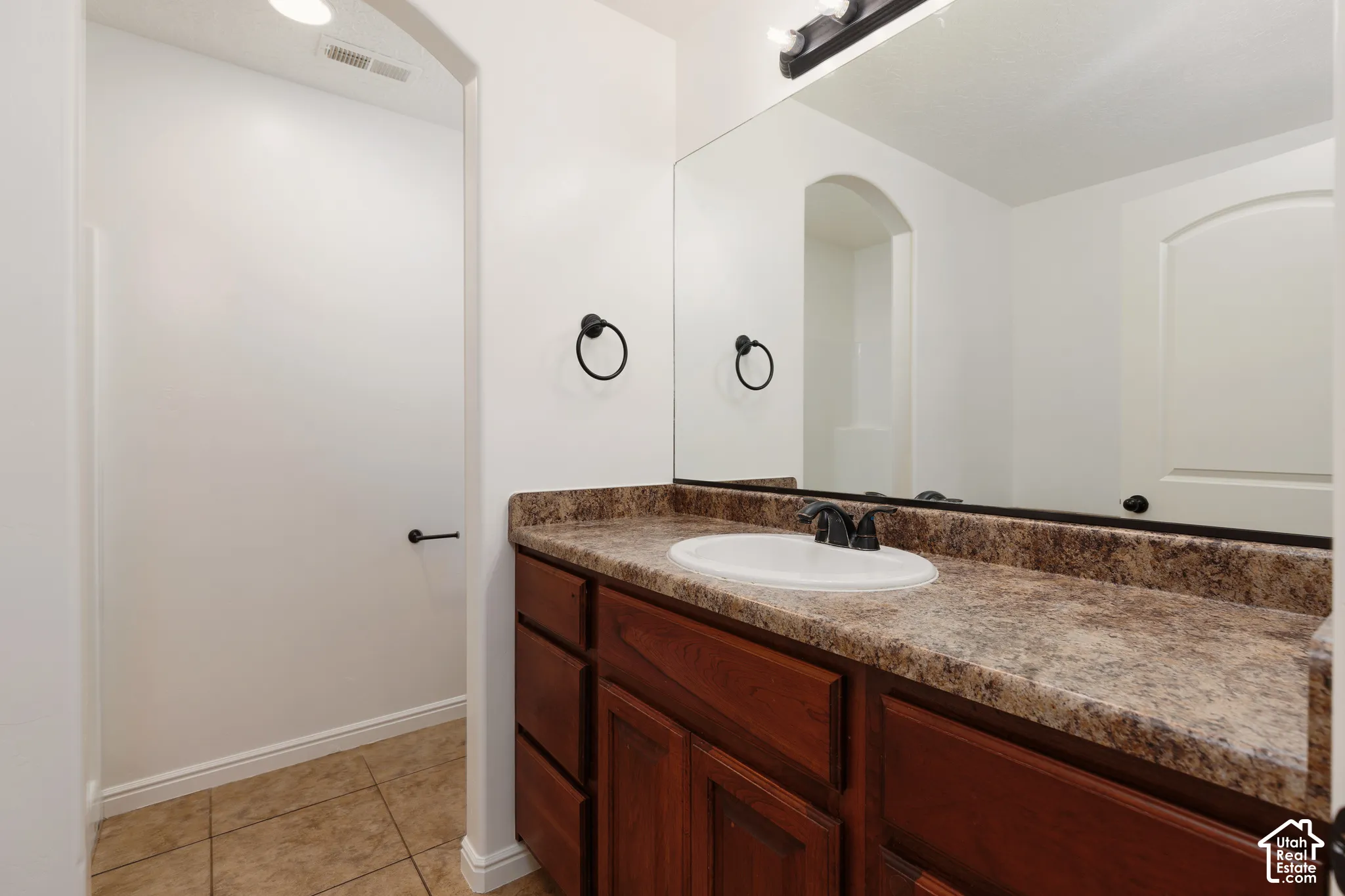 Vanity with a built-in sink, wood-finish cabinetry, and a stone-finish countertop