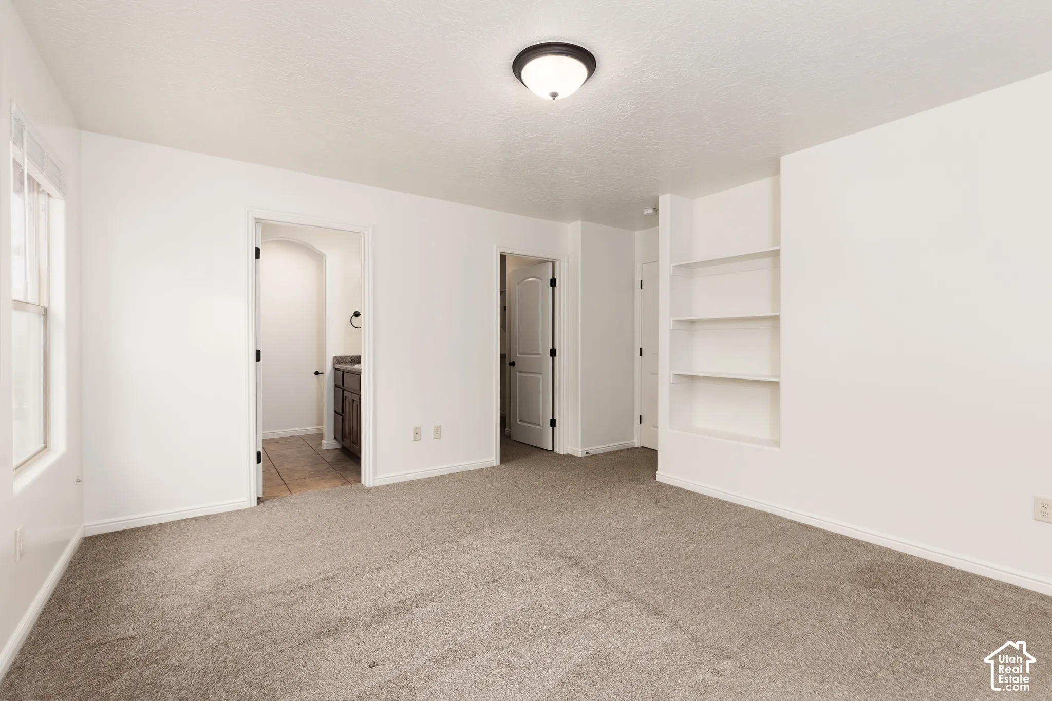 Neutral-toned carpeting throughout, complemented by built-in shelving and a contemporary ceiling fixture