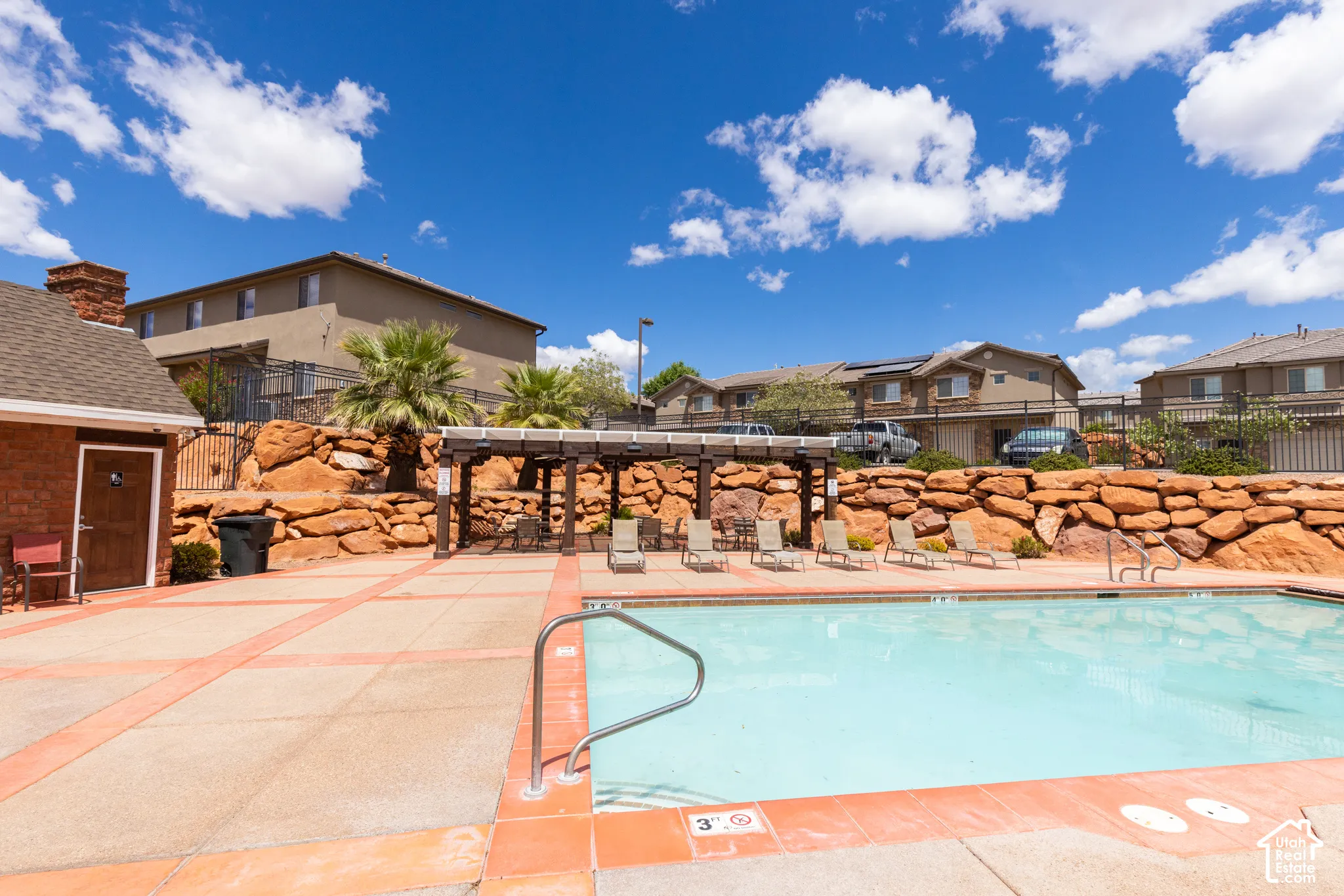 Outdoor swimming pool with integrated steps, surrounding concrete patio, and a wood pergola