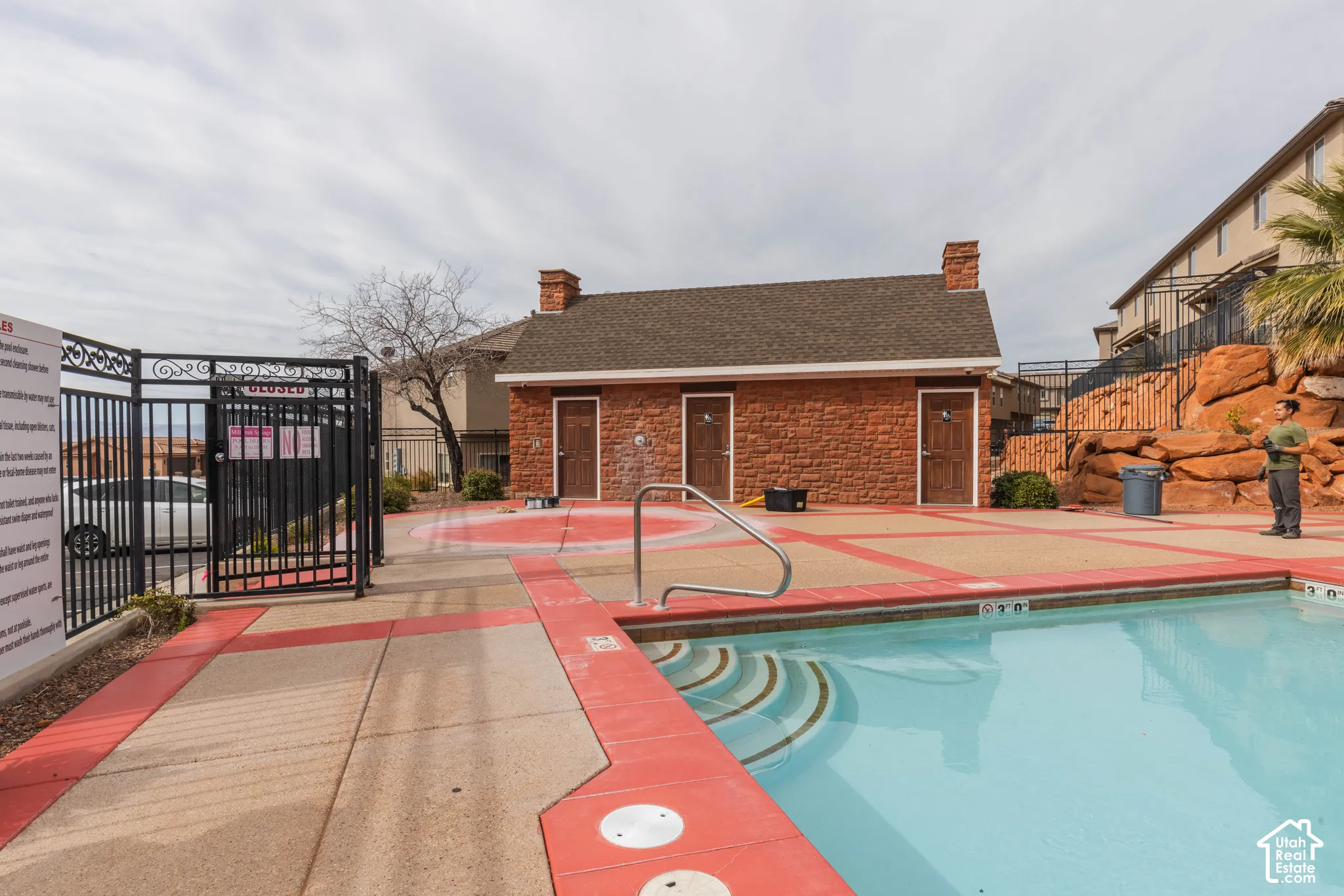 Outdoor swimming pool with integrated steps, surrounded by a red-trimmed concrete deck