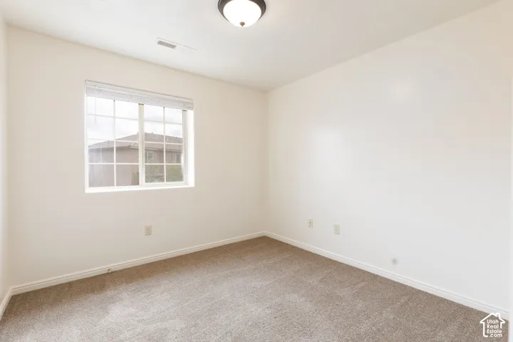 Neutral tone wall finishes, flush mount ceiling light fixture, carpet flooring, and a multi-pane window with blinds