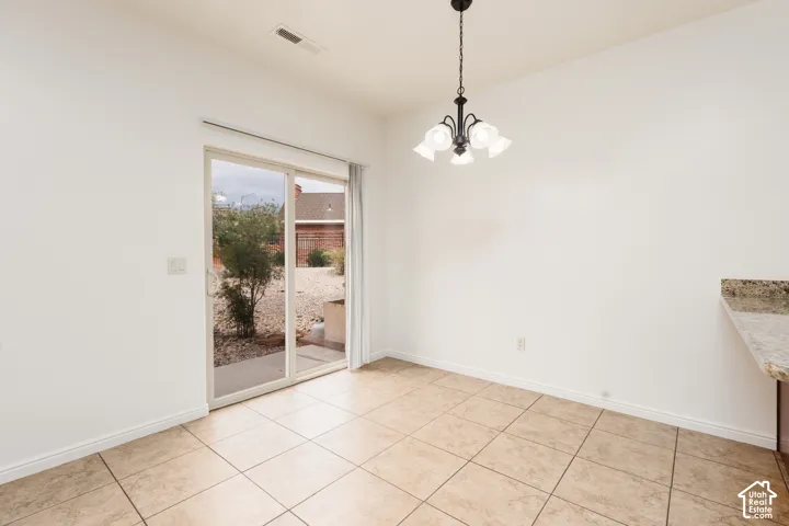 Tile flooring, sliding glass door, pendant light fixture, and a stone countertop