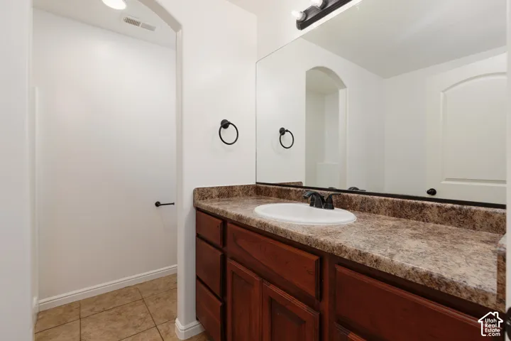Vanity with a built-in sink, wood-finish cabinetry, and a stone-finish countertop