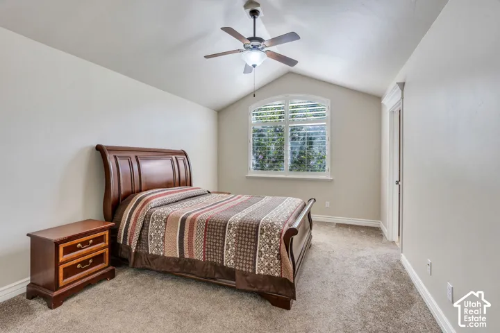 Vaulted ceiling with a ceiling fan, carpet flooring, arched window with white blinds, white trim, and a white interior door