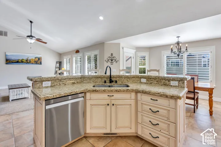 Kitchen island featuring a built-in sink with a matte black faucet, stainless steel dishwasher, and stone countertops