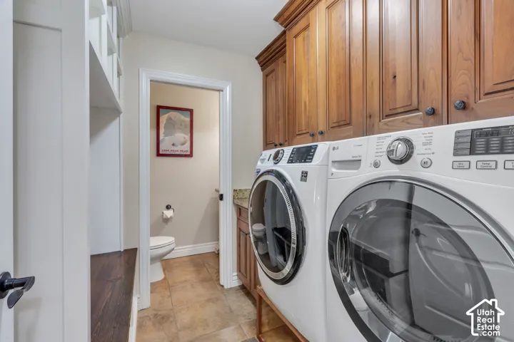 Built-in shelving, wood-finish cabinetry, under-cabinet lighting, tile flooring, and a pedestal toilet