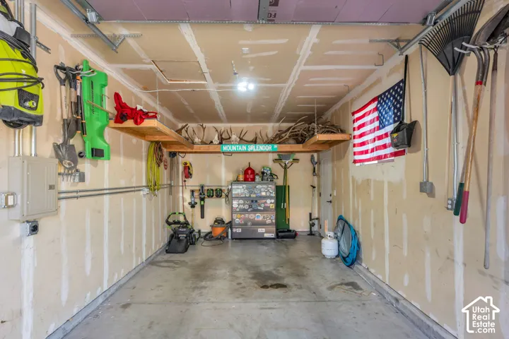 Concrete flooring, built-in overhead shelving, exposed conduit, and drywall-finished walls