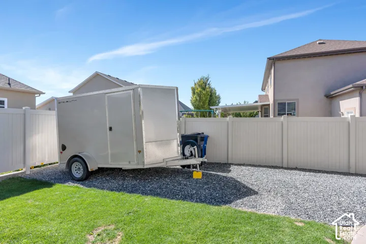 Gravel parking pad with a light-colored privacy fence