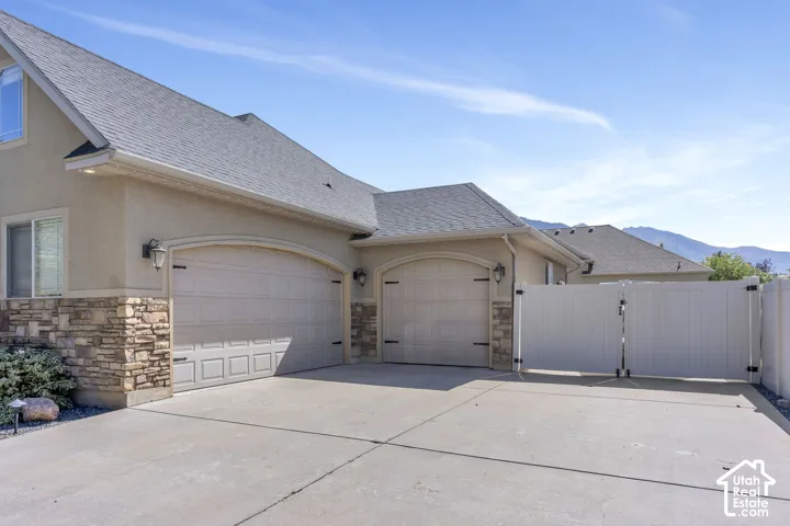 Stucco exterior with stone accents and a gray shingle roof