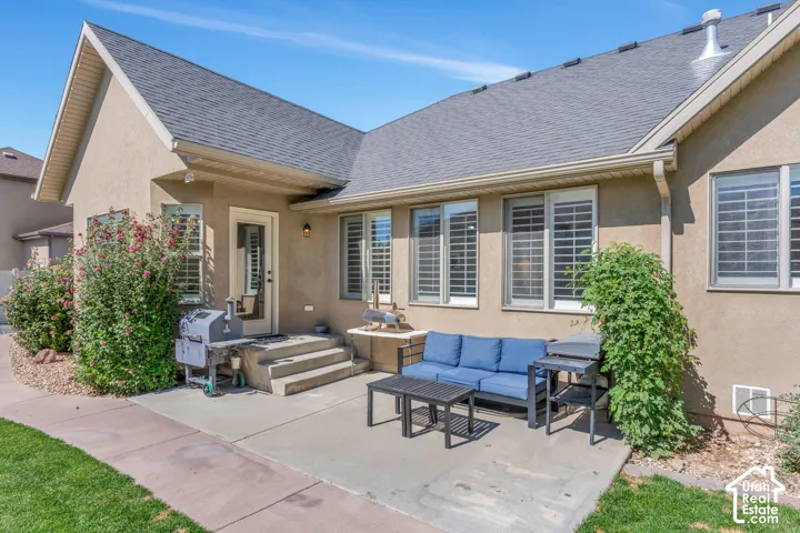 Concrete patio with a stucco exterior, multiple windows, and exterior lighting